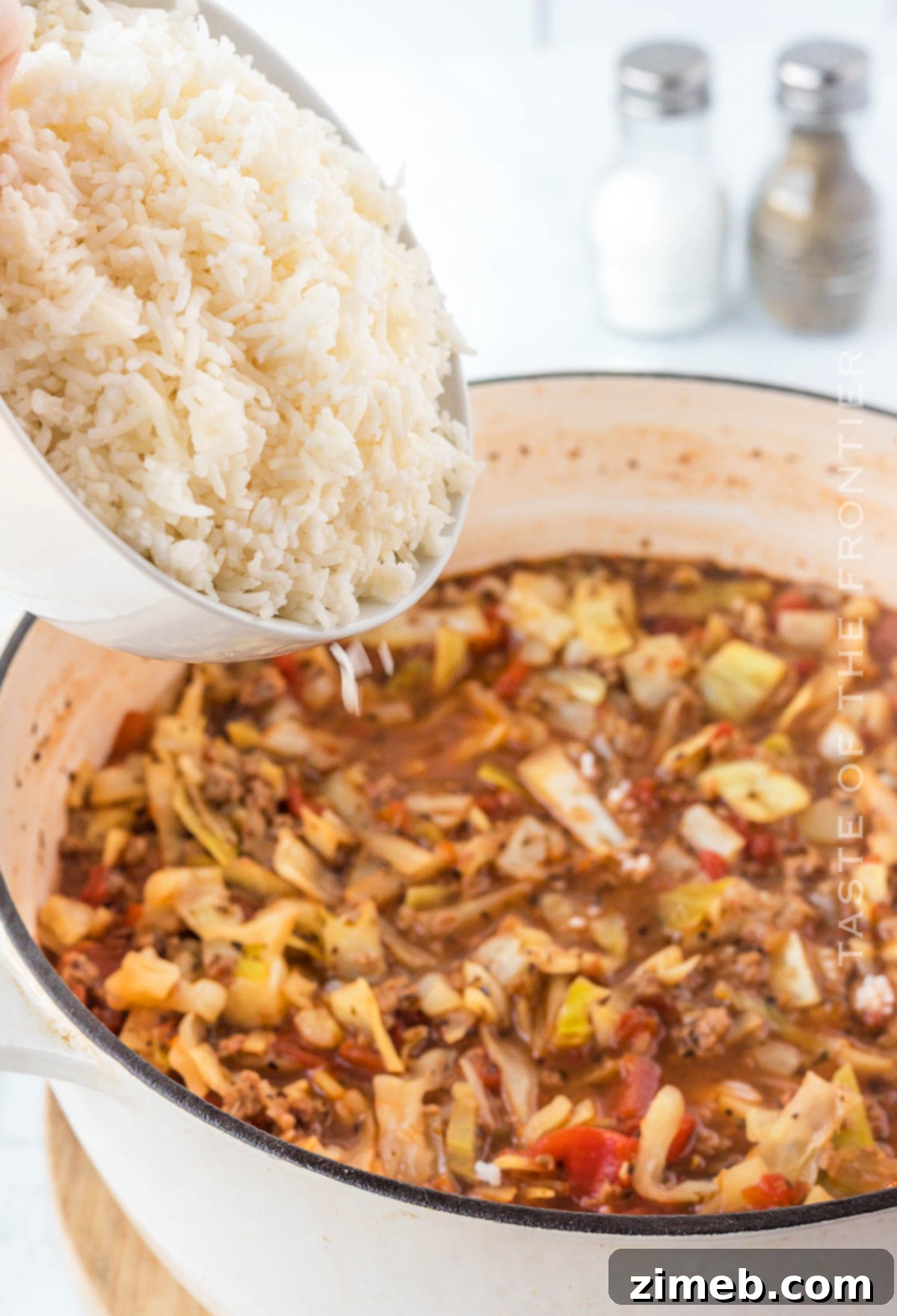 Stuffed Cabbage Soup 10 Cooked rice being stirred into unstuffed cabbage soup, adding hearty texture.