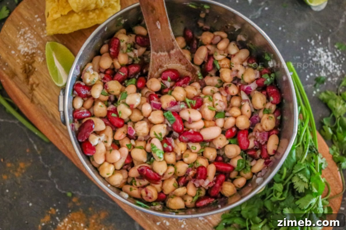 A bowl of classic Three Bean Salad, showcasing a medley of beans, red onion, and fresh herbs in a light dressing.