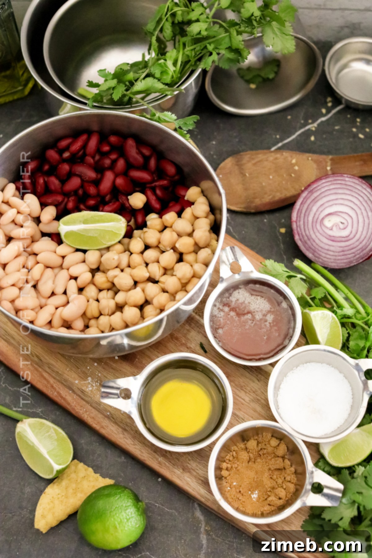 Ingredients for a fresh and zesty Three Bean Salad laid out, including various beans, cilantro, and red onion.