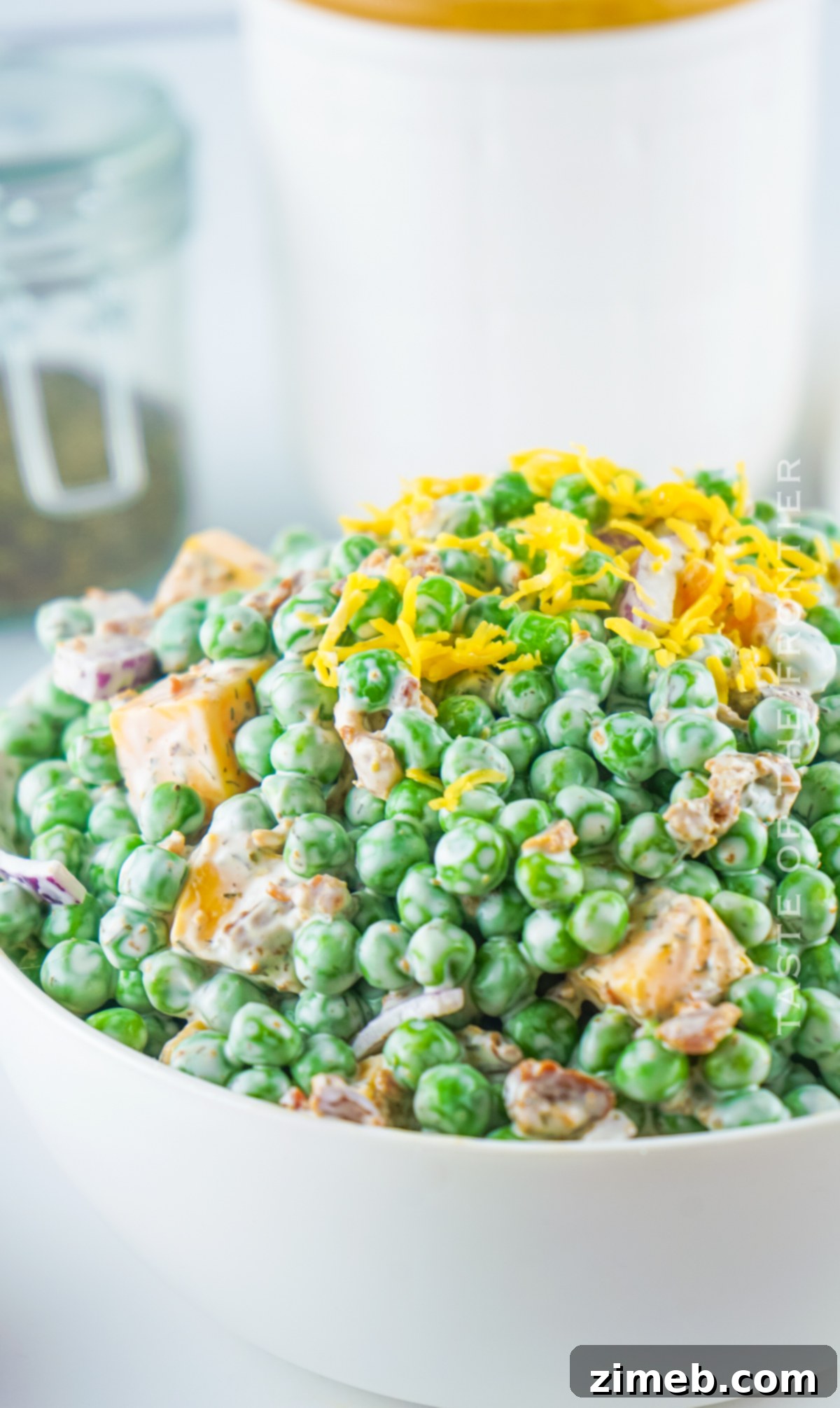 Refreshing Pea Salad 4 A bowl of sweet pea salad with cheddar cheese, bacon, and red onion, garnished with fresh dill.