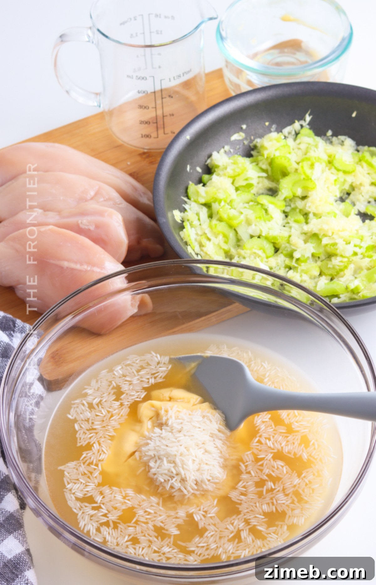 Hands preparing Chicken and Rice Casserole in a baking dish.