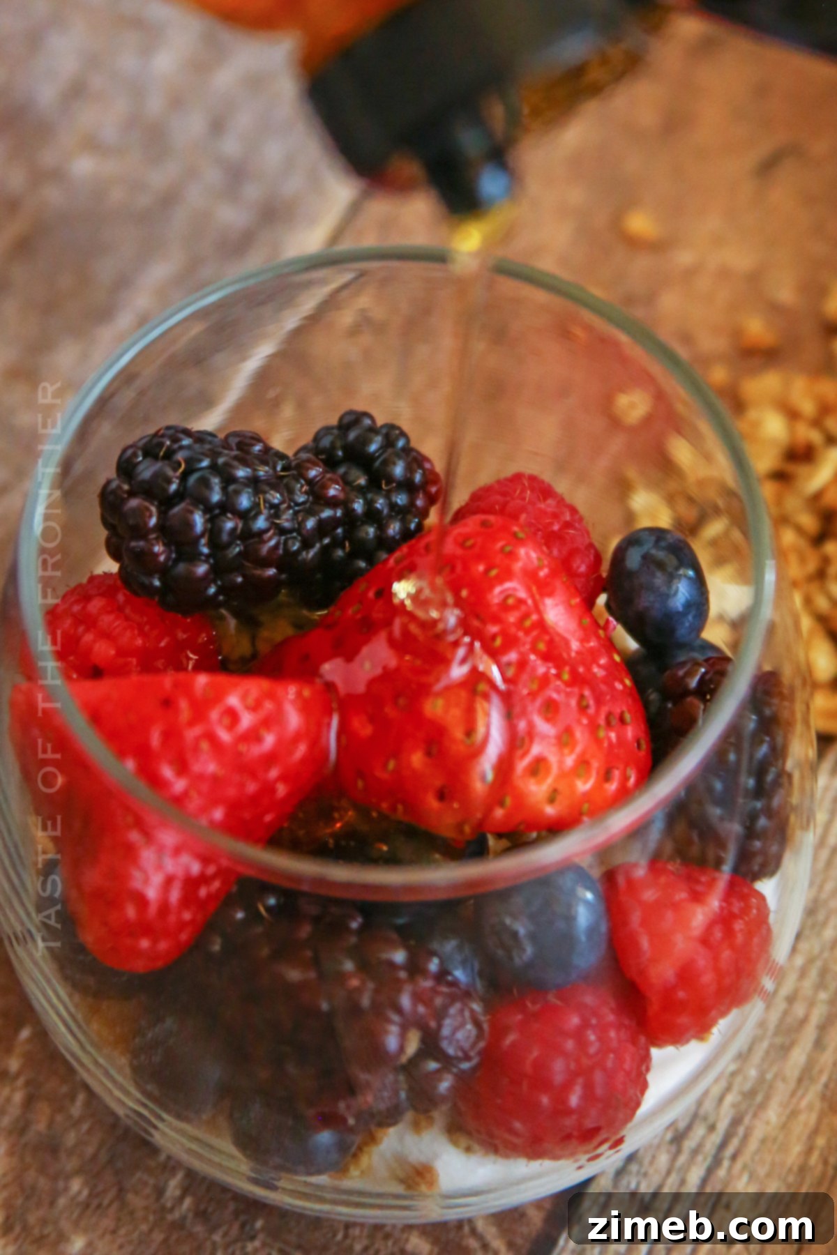 Premium Layered Dessert Glasses 7 A close-up of mixed berries and a spoonful of golden honey, key ingredients for parfait cups.