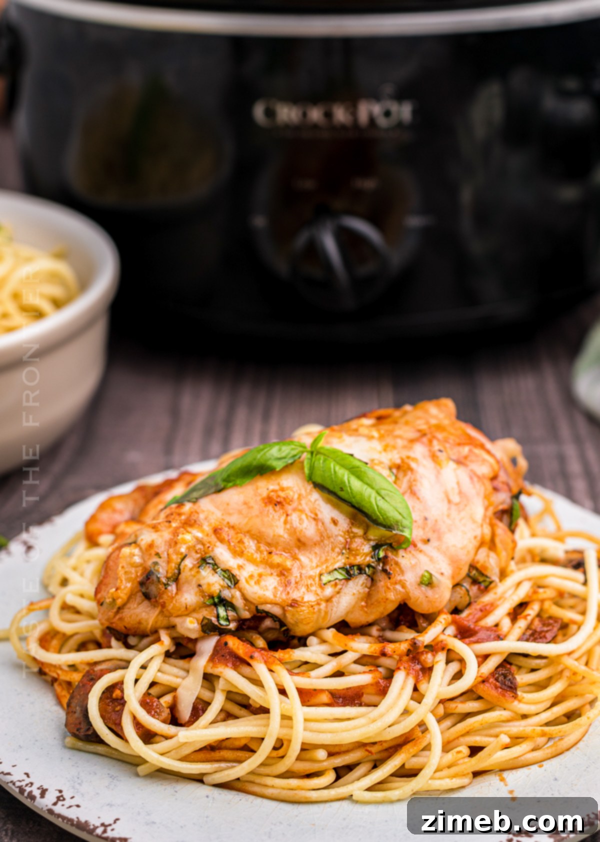 Effortless Slow Cooker Chicken Parmesan 18 Slow Cooker Chicken Parmesan served over pasta, garnished with fresh basil