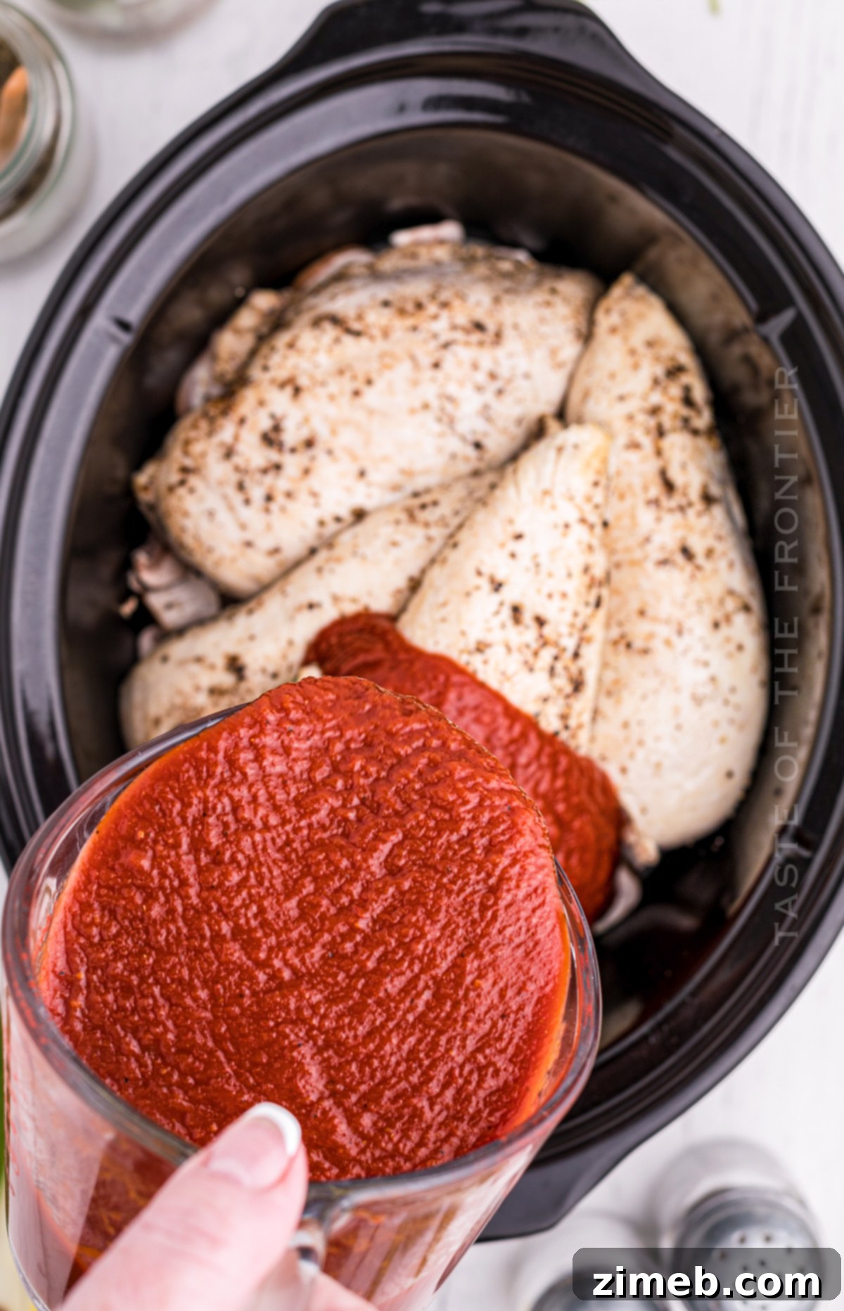 Effortless Slow Cooker Chicken Parmesan 6 Adding rich pasta sauce to chicken in the slow cooker