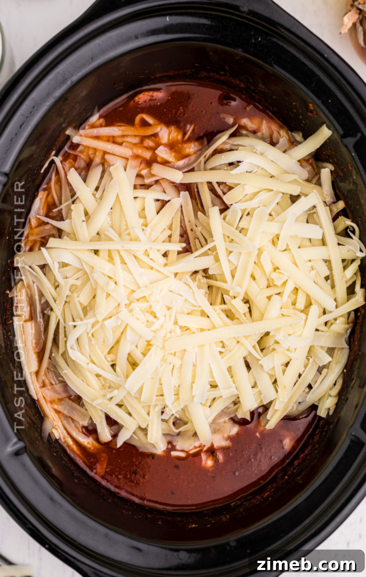 Effortless Slow Cooker Chicken Parmesan 7 Adding shredded parmesan cheese to chicken parm
