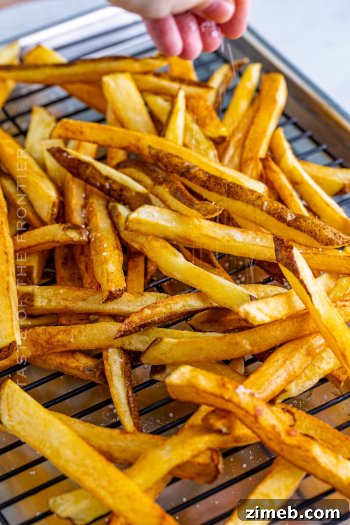 Poutine: Canada's Cheesy, Gravy-Laden Delight 8 Salting freshly made homemade french fries for poutine