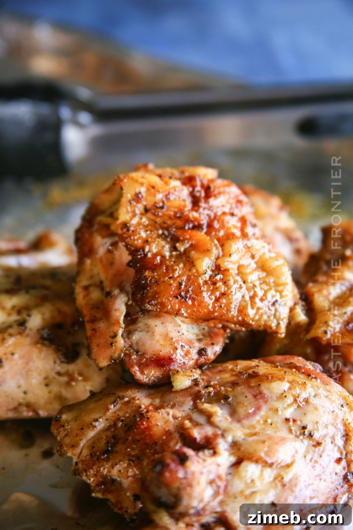 Juicy Smoked Chicken Thighs 3 Two Traeger Smoked Chicken Thighs resting on a wooden board, showcasing their golden-brown skin and juicy texture
