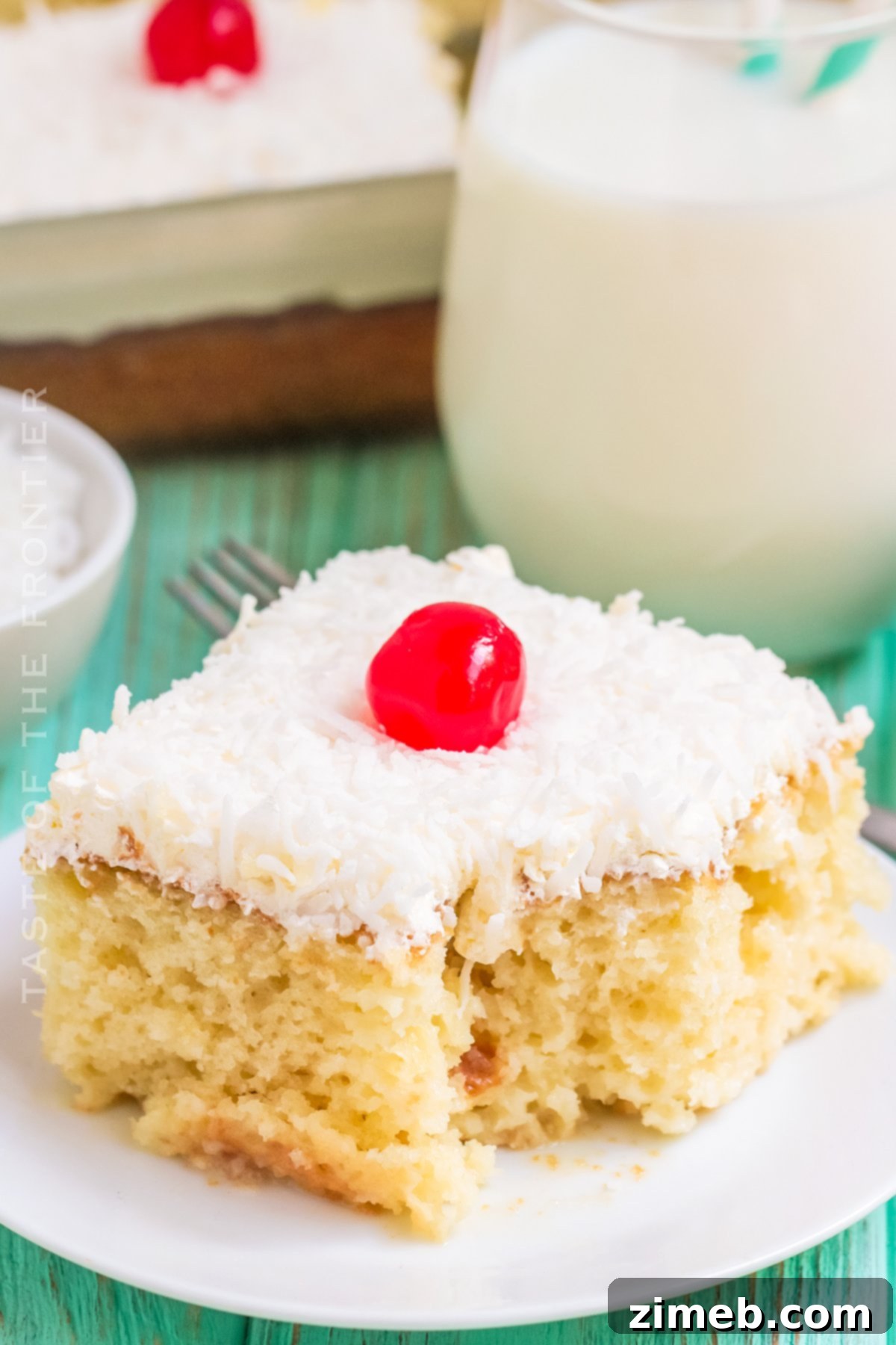 Delightful Coconut Poke Cake topped with whipped cream and a cherry, perfect for any celebration.