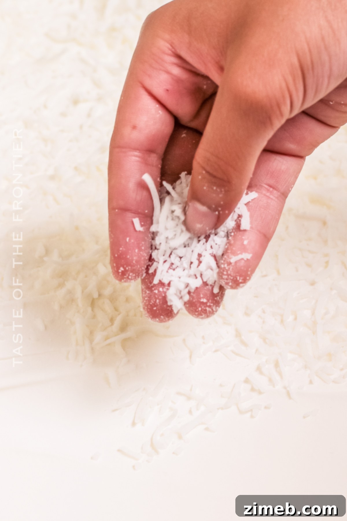 Topping the Coconut Poke Cake with whipped cream and shredded coconut.