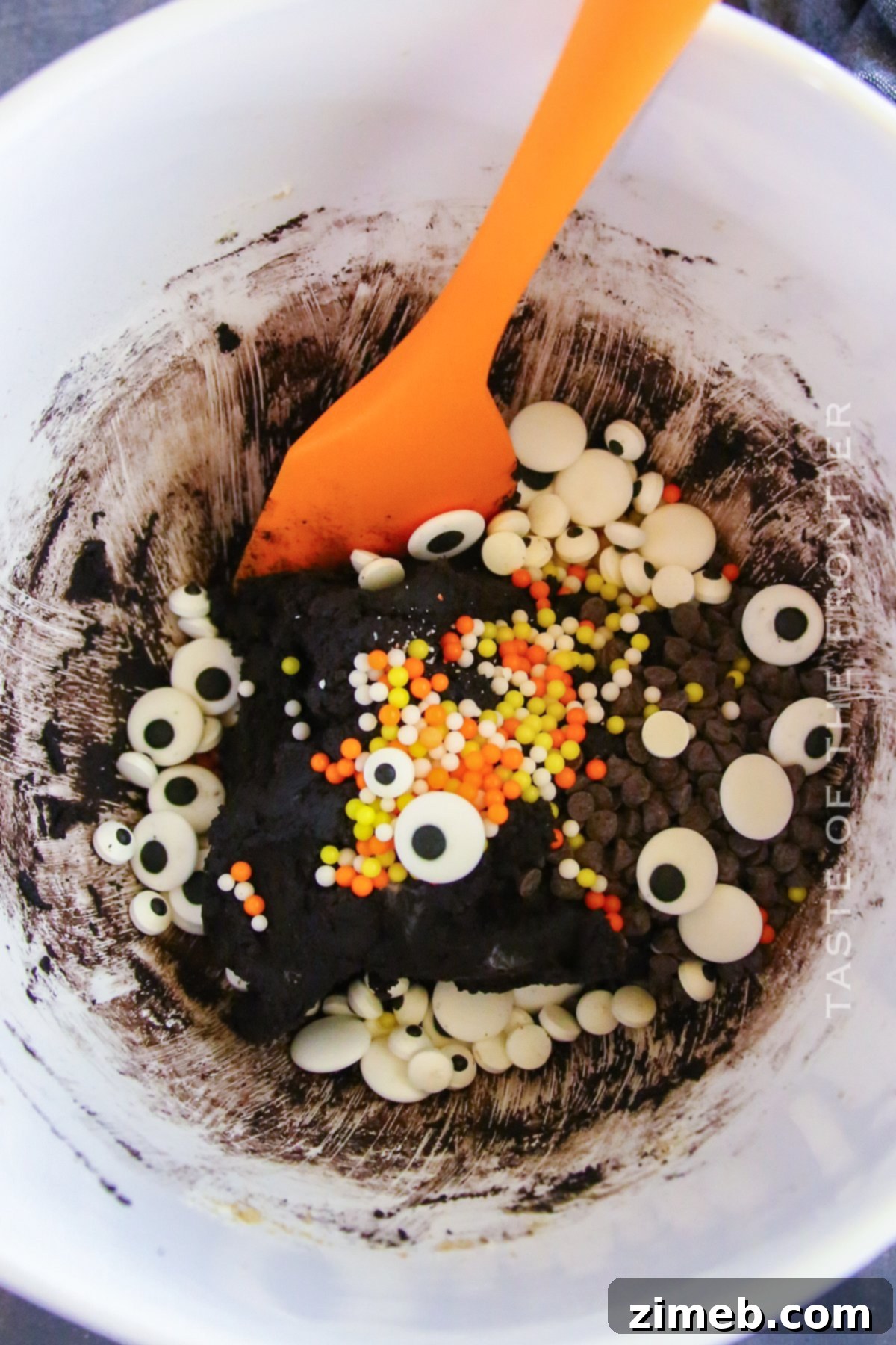 Edible Halloween Cookie Dough 5 Hands mixing ingredients in a bowl for Halloween Cookie Dough, showing the dark cocoa and other components.