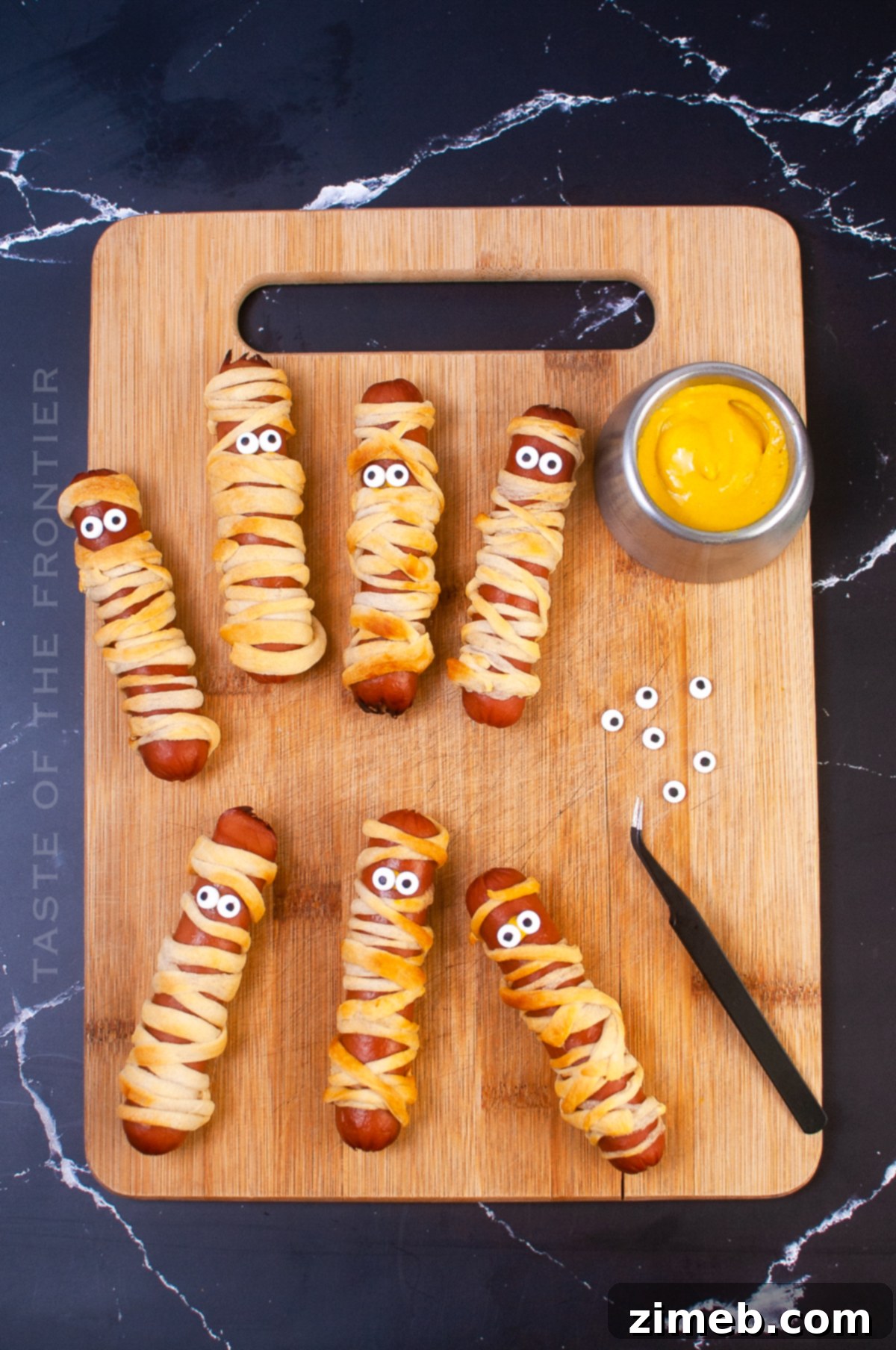 Phantom Franks 18 Adding candy eyeballs to freshly baked Mummy Dogs, creating their spooky look.