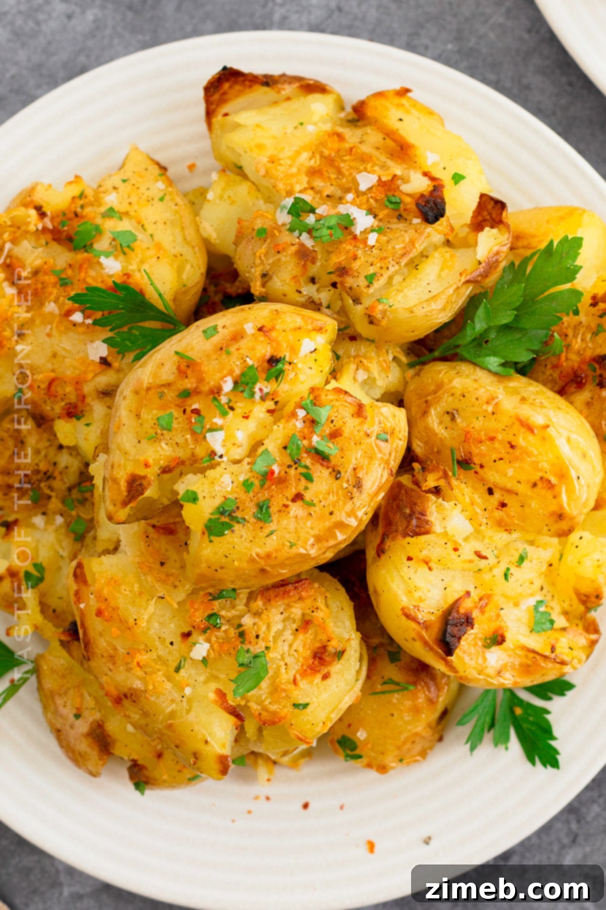 Crispy Smashed Potatoes 2 A serving of beautifully golden and crispy Smashed Potatoes, garnished with fresh herbs, ready to be enjoyed.