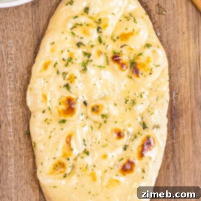 Freshly baked Garlic Butter Naan bread, soft and pillowy, on a plate, ready to be served.