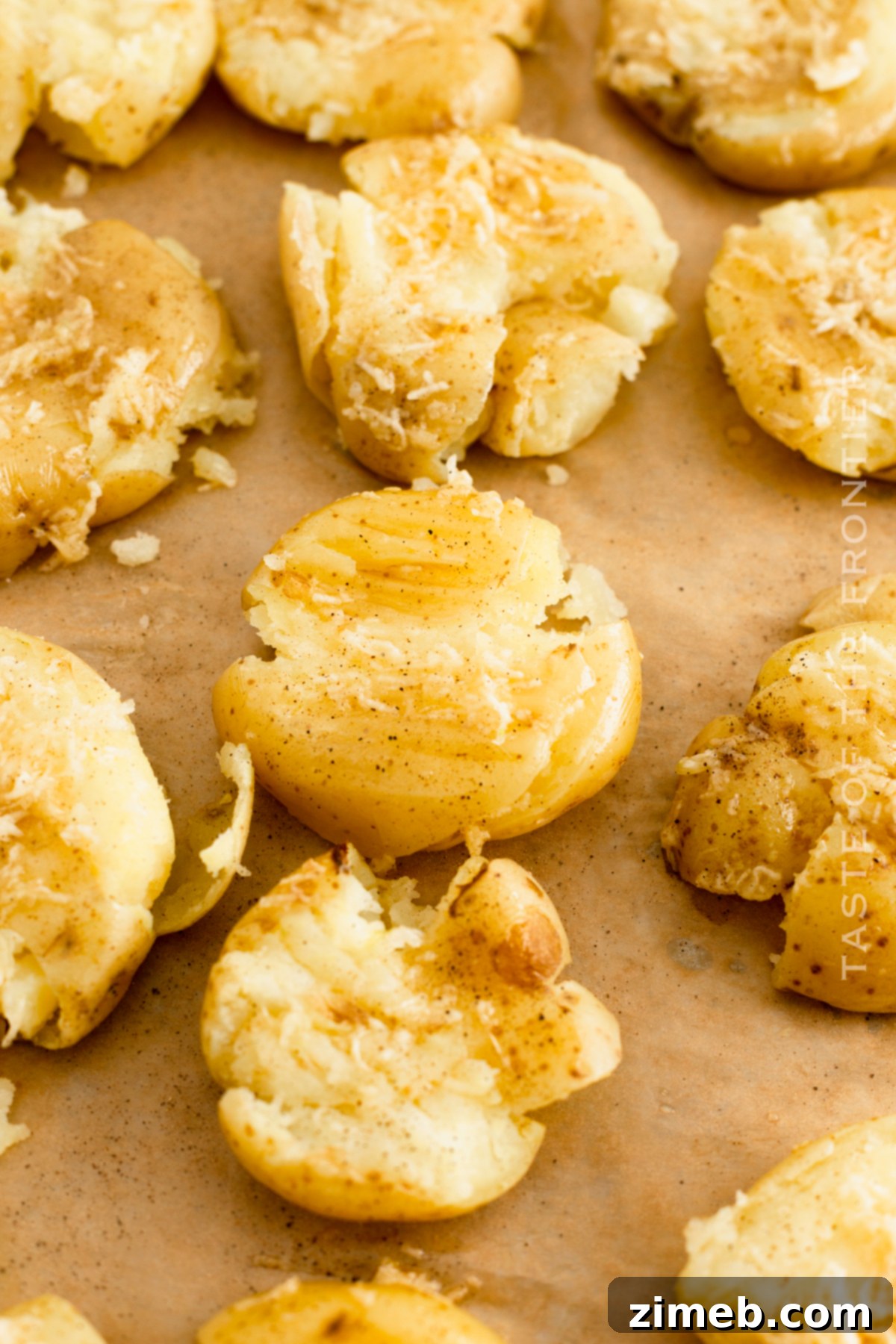 Crispy Smashed Potatoes 6 A hand gently smashing a boiled baby potato on a parchment-lined baking sheet, showing the preparation step for crispy smashed potatoes.