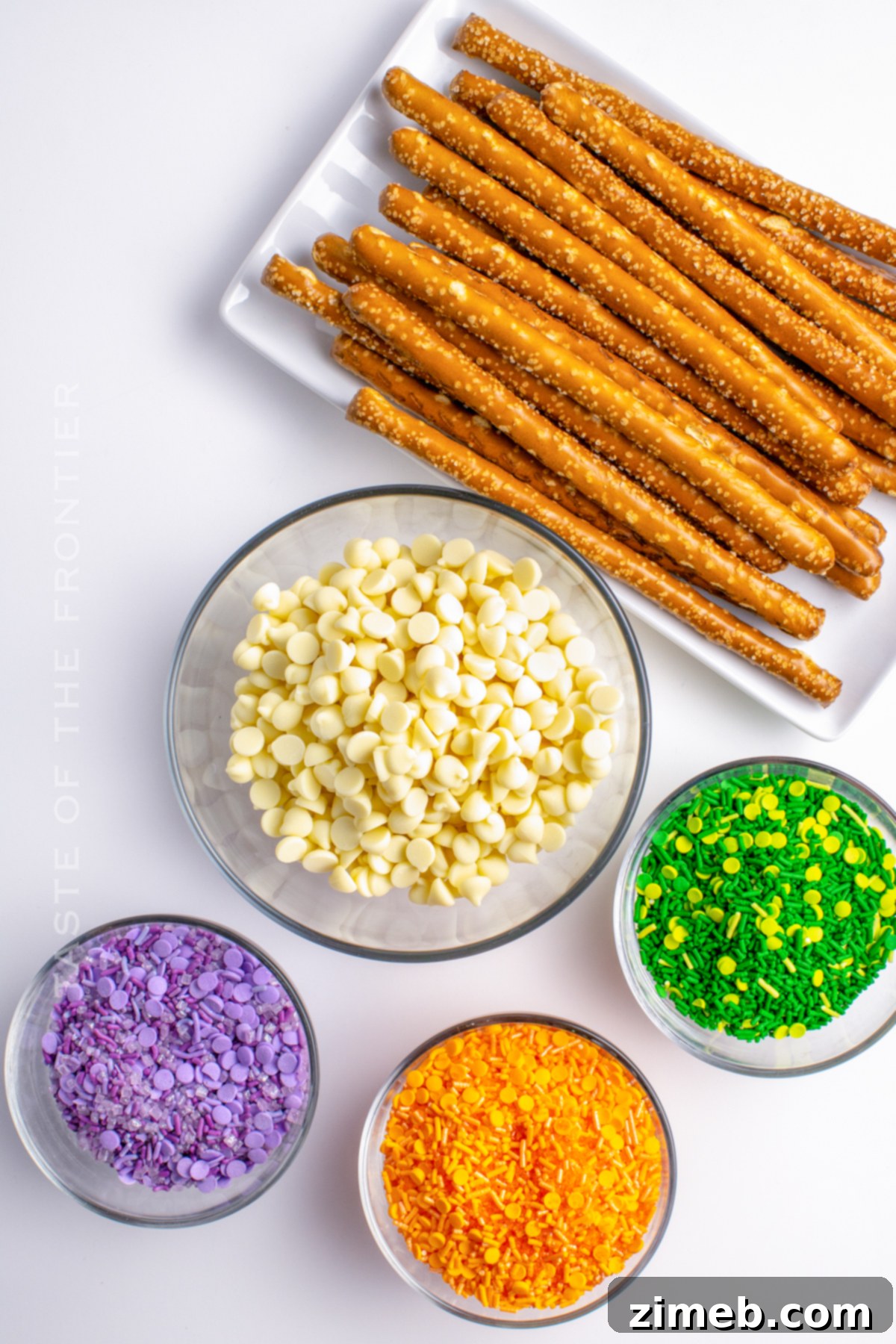 Ingredients for making Halloween Pretzels, including white chocolate chips, pretzel rods, and colorful sprinkles