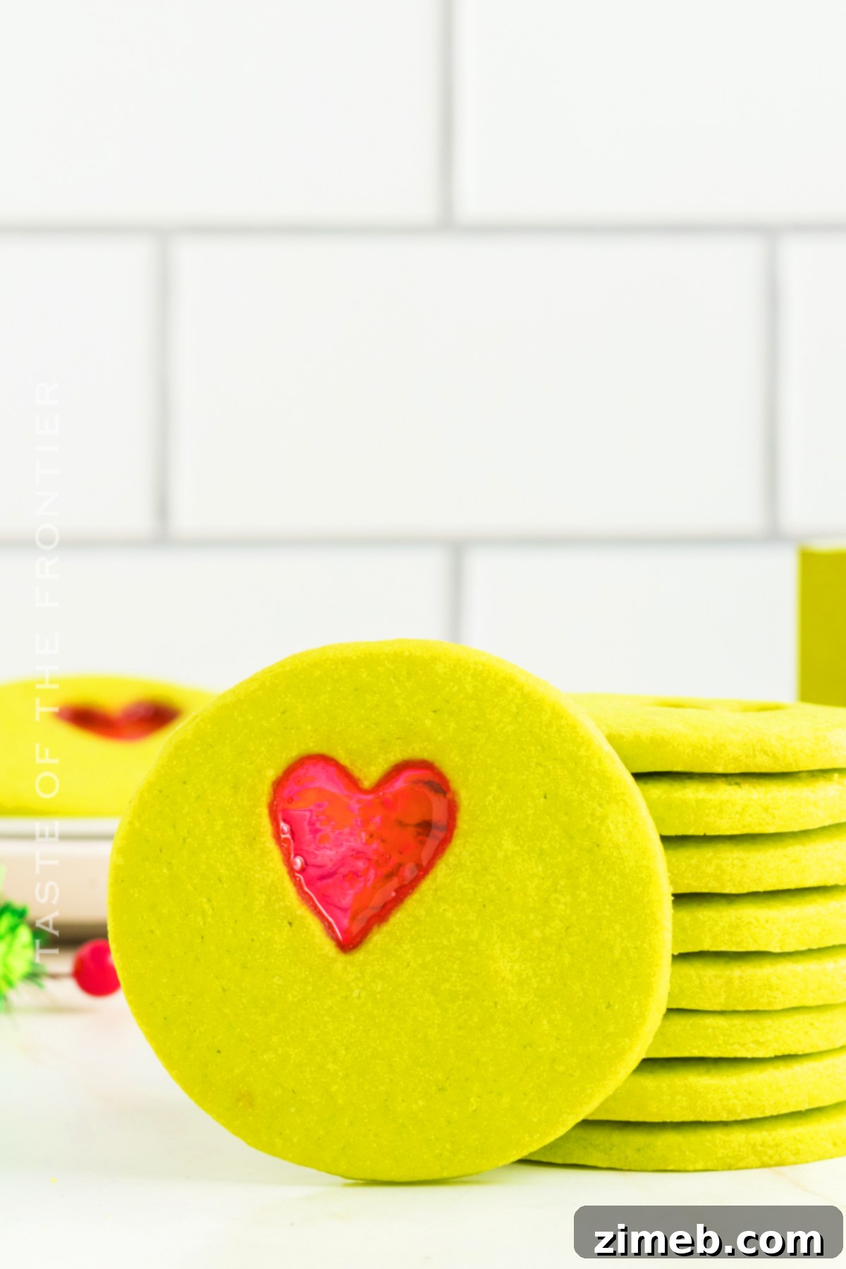 Beautifully baked Grinch Christmas Cookies with glistening red heart centers.