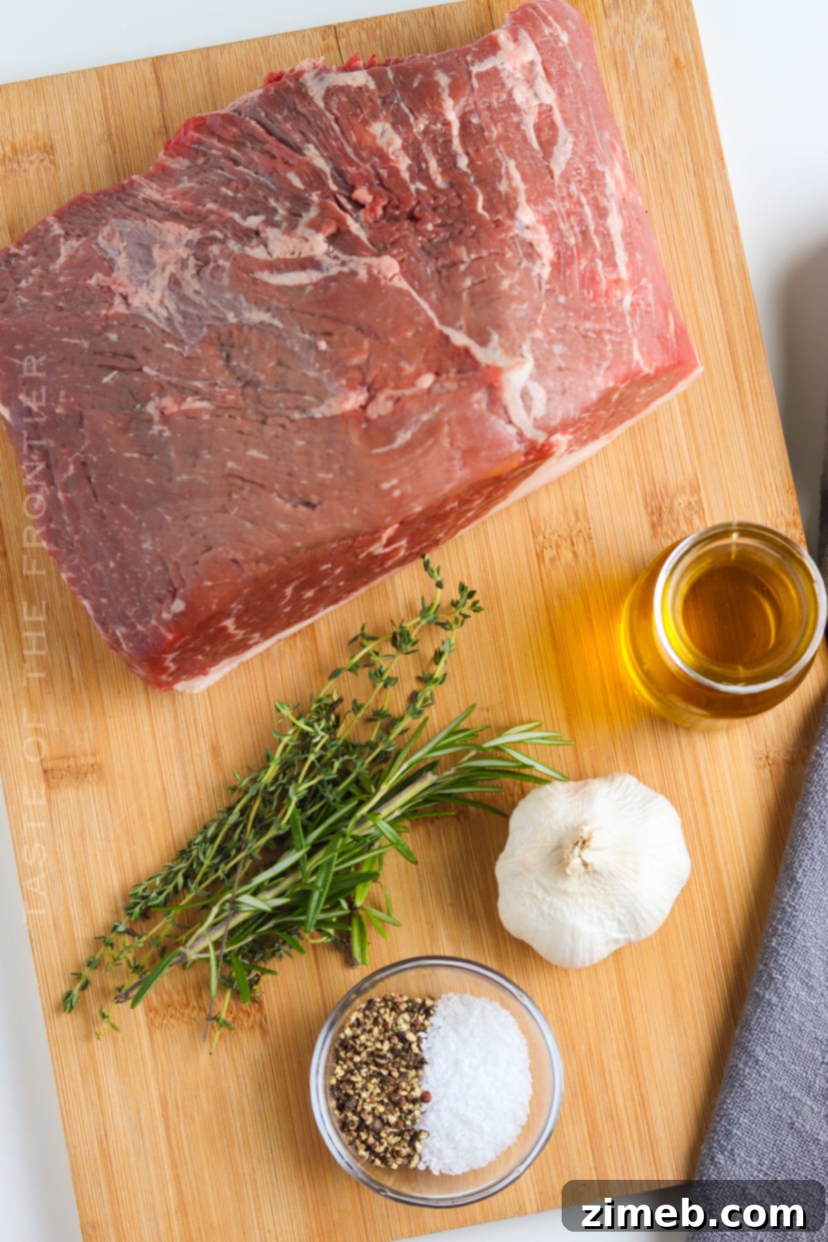 Ingredients for Easy Oven Roast Beef, including fresh herbs, garlic, and olive oil, arranged neatly.