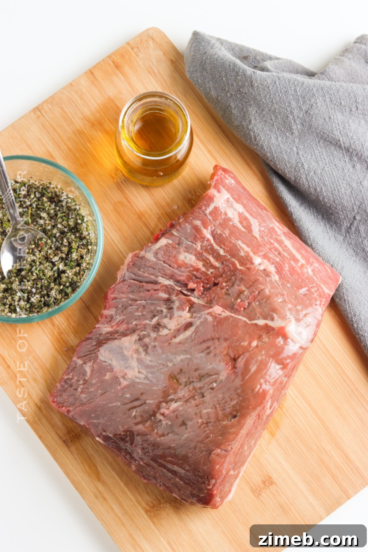 A hand gently oiling the oven roast beef with olive oil and the herb mixture before cooking.