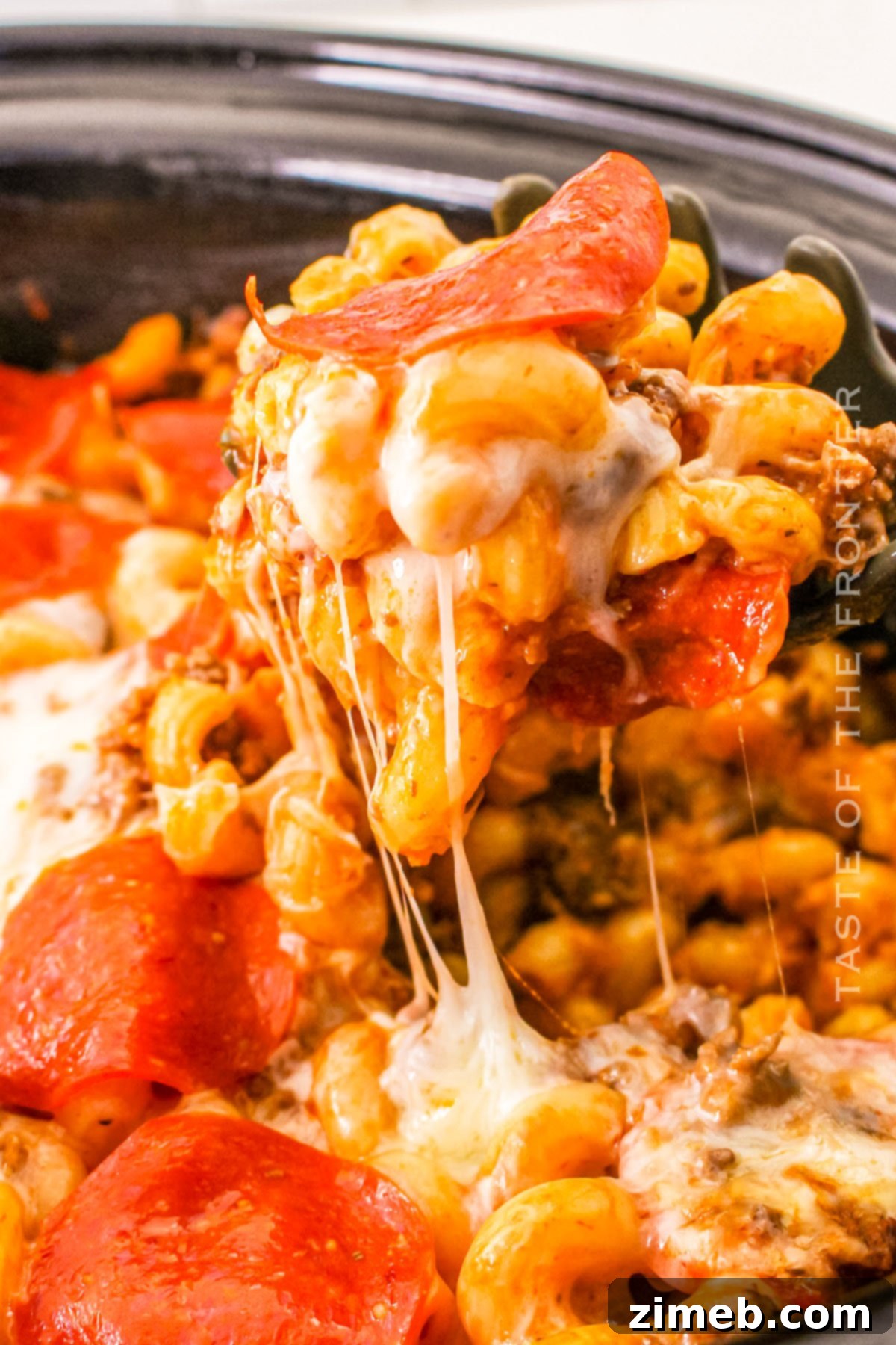 Cheesy Pizza Bake 3 Close-up of a slow cooker casserole, showcasing the layers of pasta, meat, sauce, and cheese before cooking.