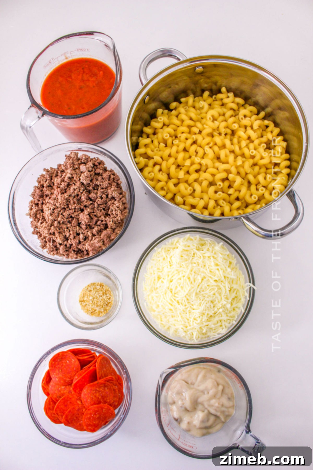 Cheesy Pizza Bake 4 Ingredients laid out for Pizza Casserole made in the Crockpot, including pasta, ground beef, pepperoni, cheese, and sauce.