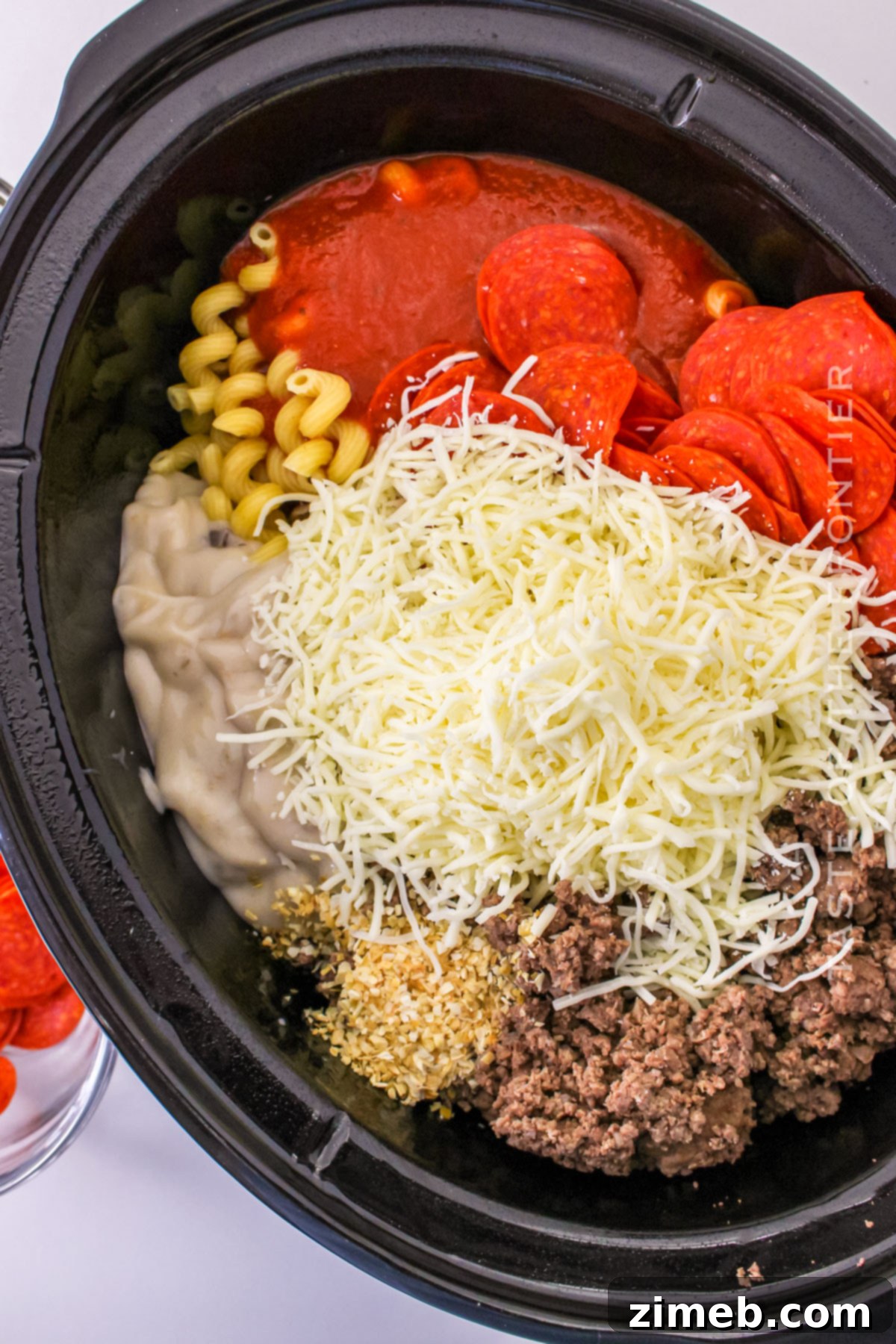 Cheesy Pizza Bake 5 Making casserole in the slow cooker, showing ingredients being mixed together.