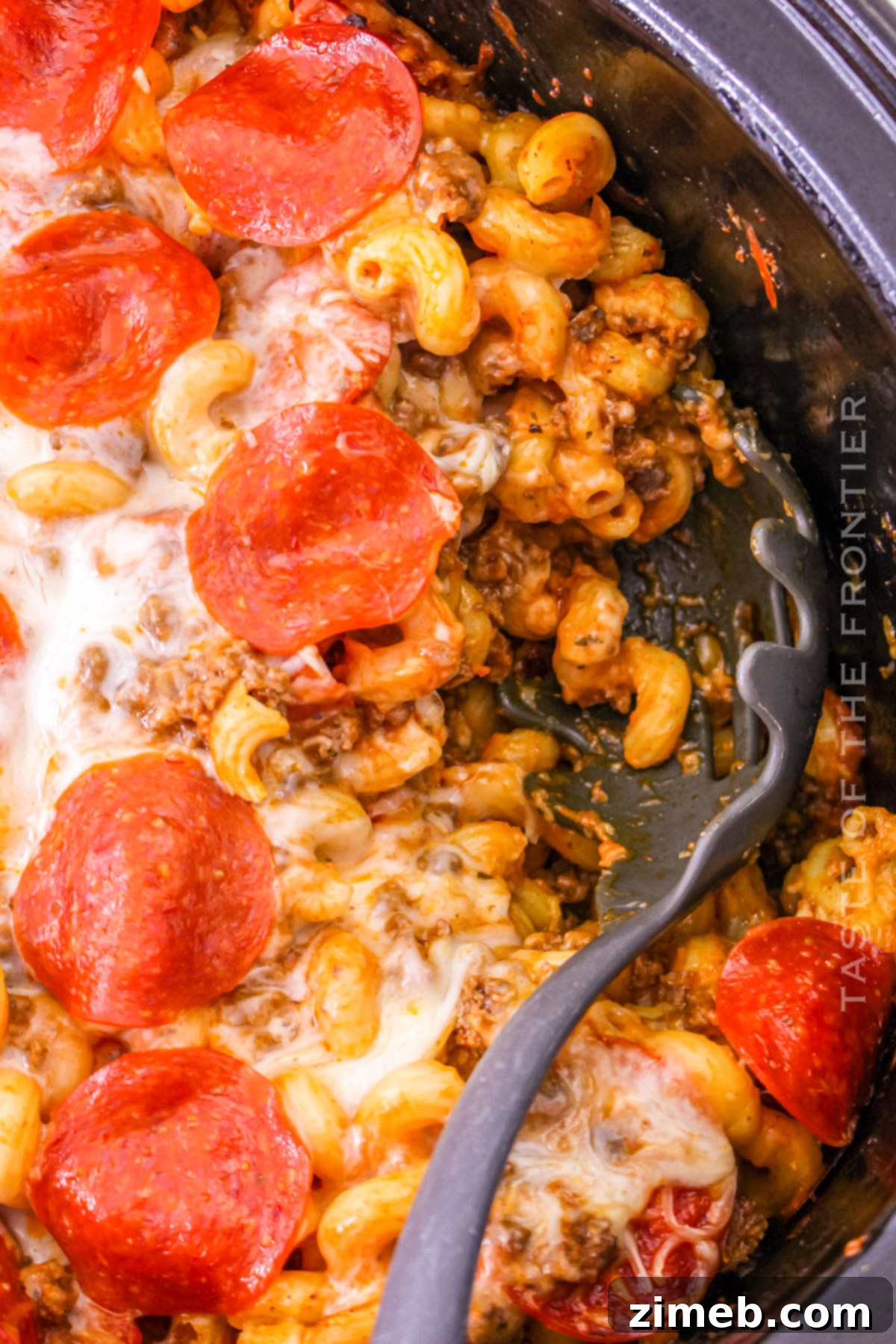 Cheesy Pizza Bake 7 A serving of Pizza Casserole from the Crockpot on a plate, garnished with fresh herbs.