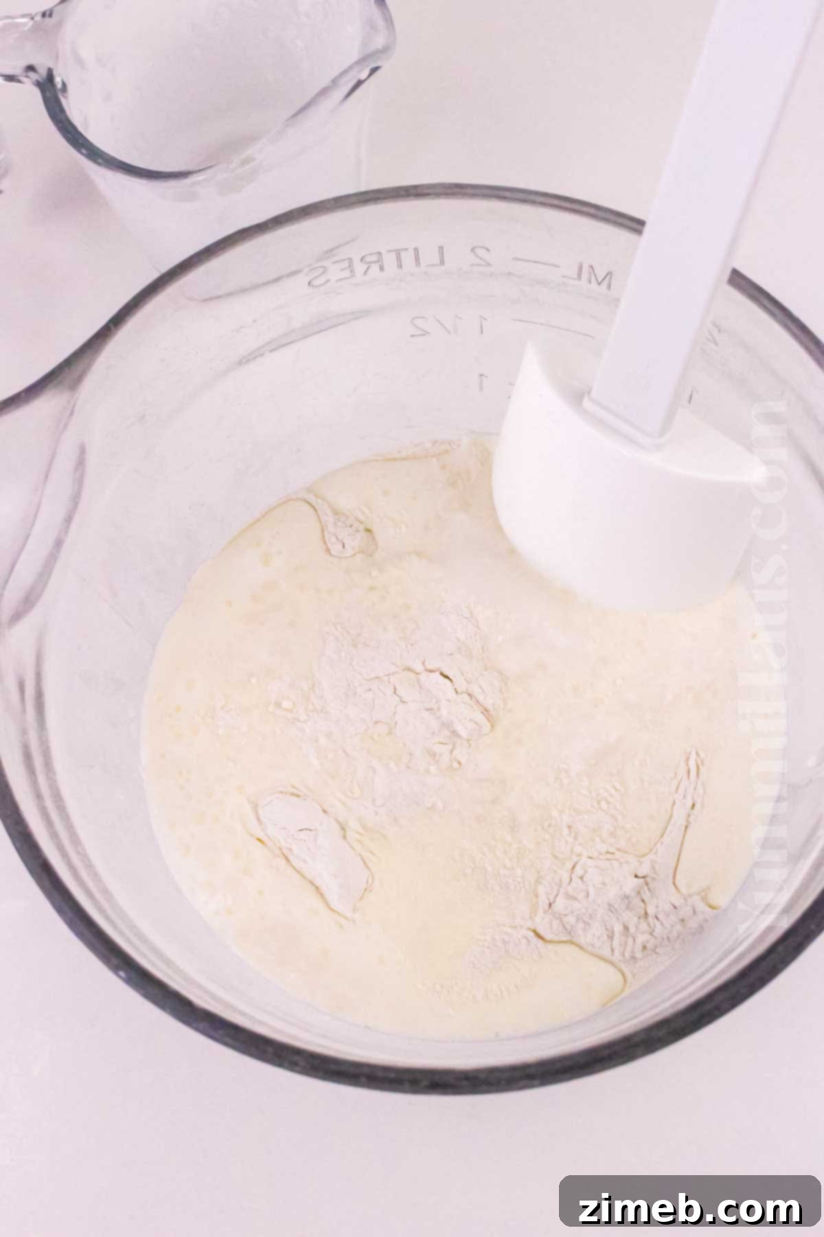 Minimalist Biscuits 5 Hands gently kneading biscuit dough on a floured surface, preparing it for cutting.