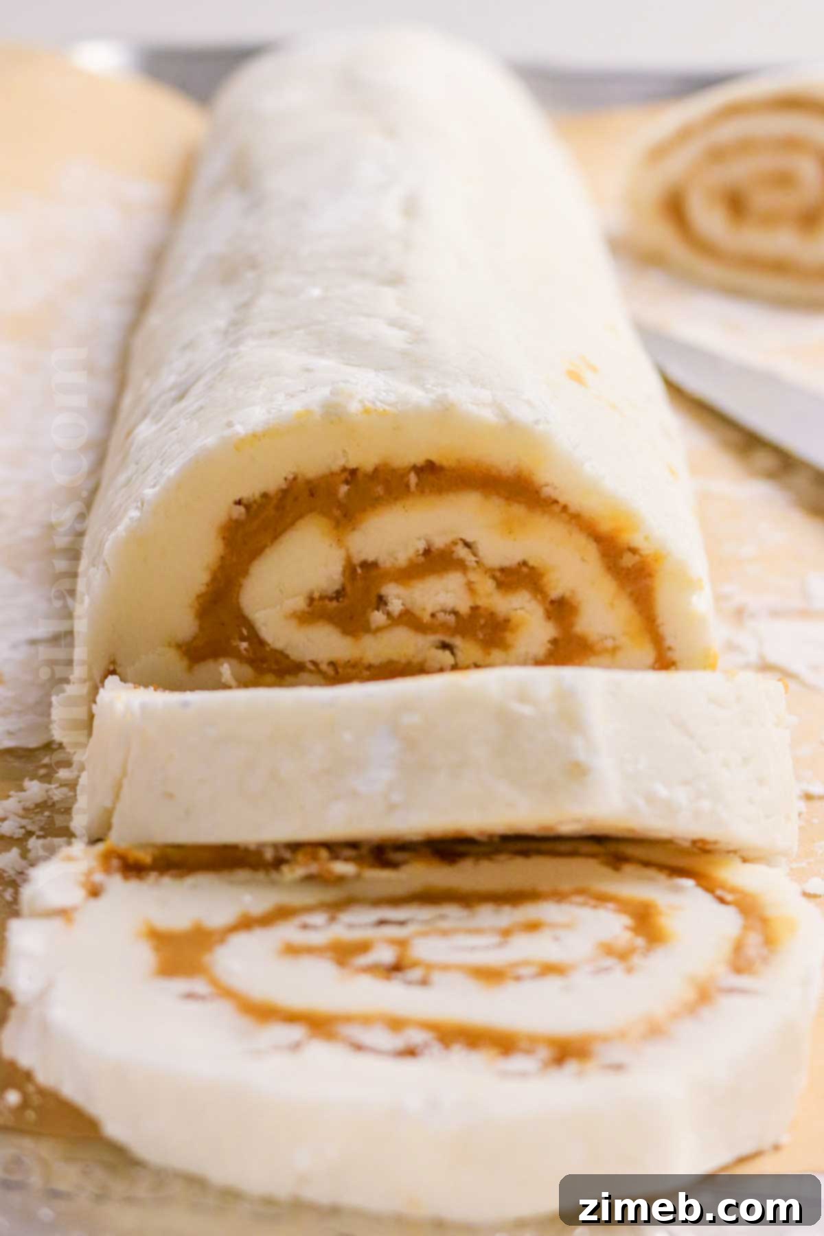 Potato Truffles 7 Slicing a chilled potato candy log into creamy peanut butter pinwheels on a cutting board.