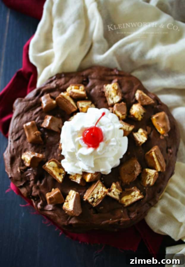 A delicious Snickers Brownie for Two in a small cast iron skillet, garnished with whipped cream and a bright red cherry, ready for a romantic dessert.
