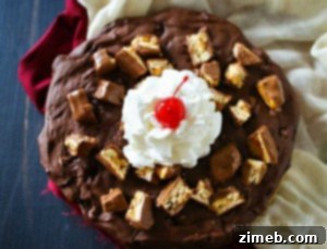 A top-down view of a freshly baked Snickers Brownie for Two, still in the skillet, ready to be adorned with toppings.