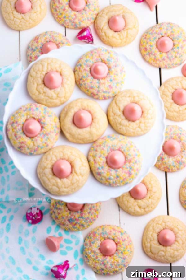 Pink kiss cookies with strawberry chocolate kisses on a baking tray