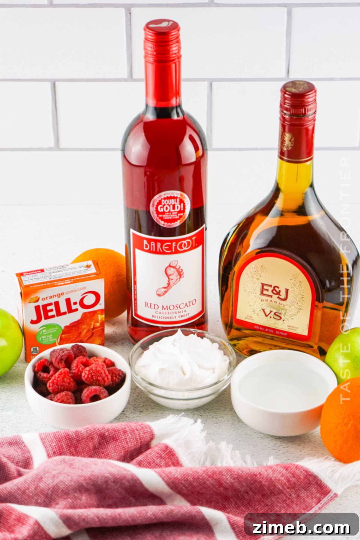 A selection of fresh ingredients like orange jello, red wine, and brandy, ready for Sangria Jello Shots preparation.