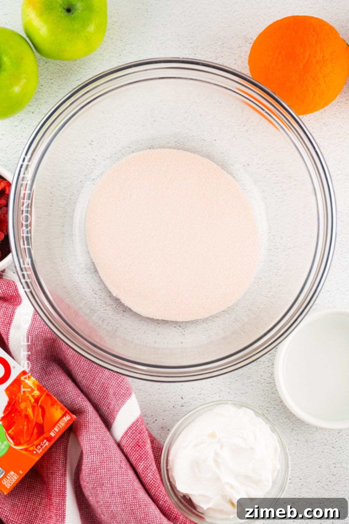 Orange Jell-O powder dissolving in hot water in a mixing bowl for Sangria Jello Shots.