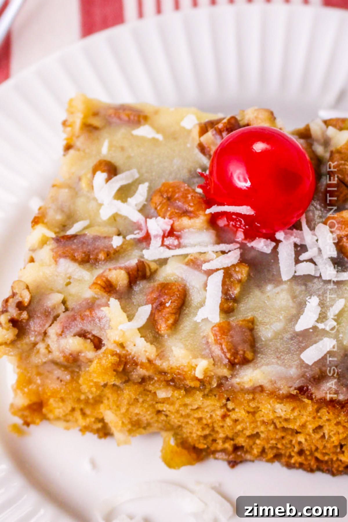 A slice of Fruit Cocktail Cake topped with a maraschino cherry.